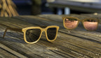 Two pairs of Iris hemp sunglasses on a dock, Shaded Black lenses in the foreground